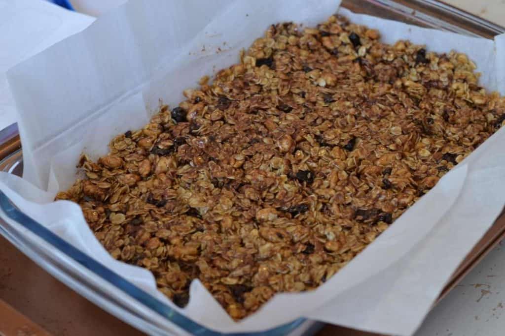 The pressed granola in a glass 9x13 baking dish lined with parchment paper