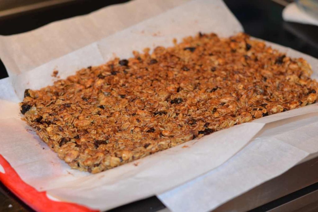 The granola bars lifted out of the dish they set in and are on a cutting board now ready to slice.