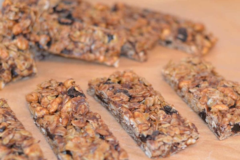 Close up of Cherry Chocolate Chip Granola Bars sliced up on parchment paper lined up in a row.