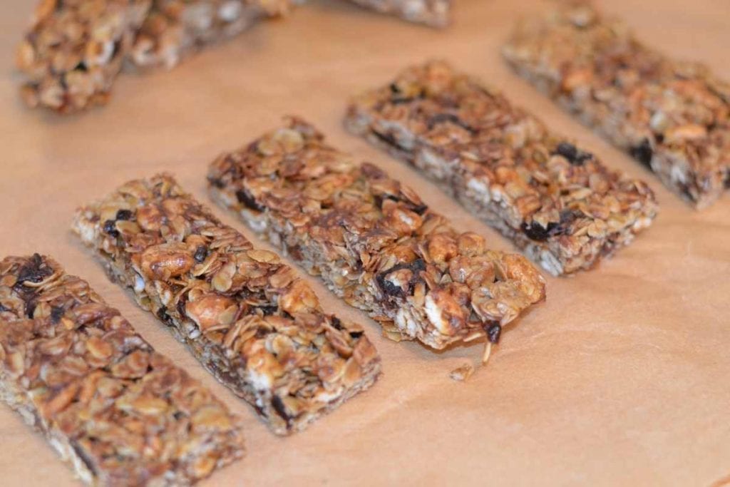 Cherry Chocolate Chip Granola Bars sliced up on parchment paper lined up in a row.