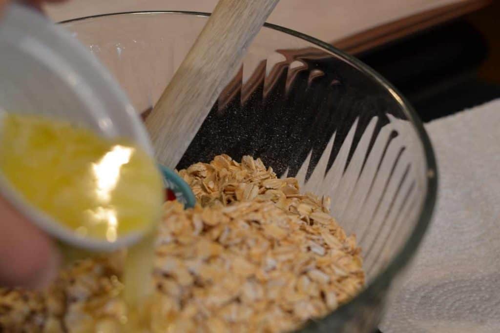 a glass bowl of oatmeal with melted butter being poured over the oats