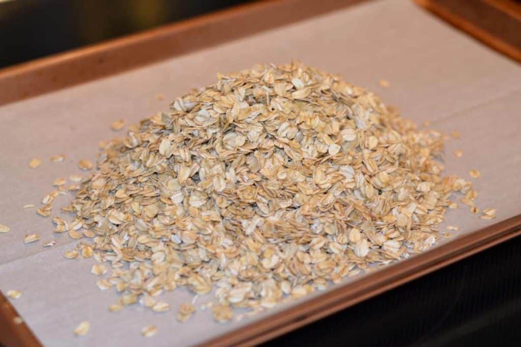 Oatmeal coated in melted butter that has been dumped onto a parchment lined sheet pan