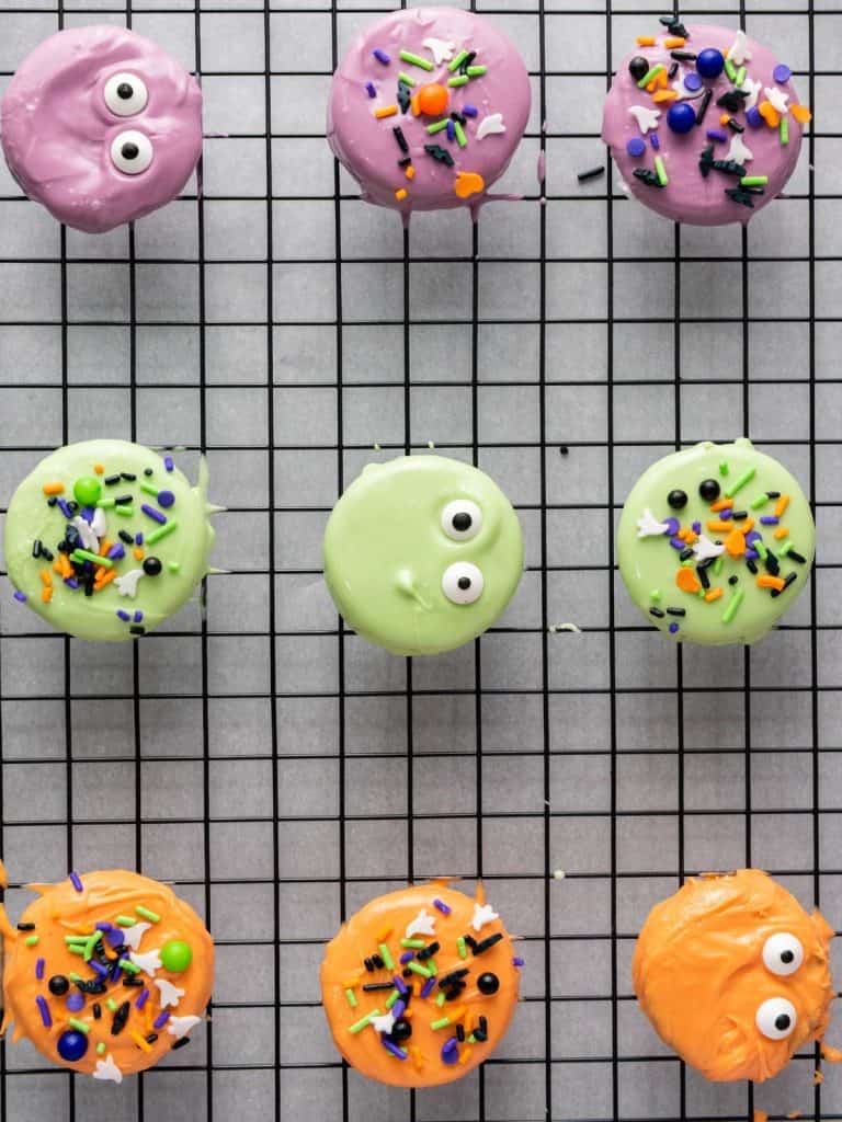 Halloween Oreos on a cooling rack decorated with sprinkles and candy eyeballs.