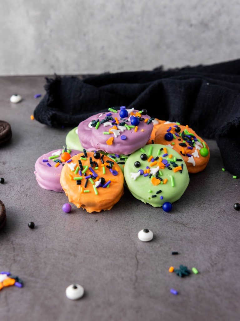 Stacked Halloween Oreos in orange, purple, and green candy coating with sprinkles